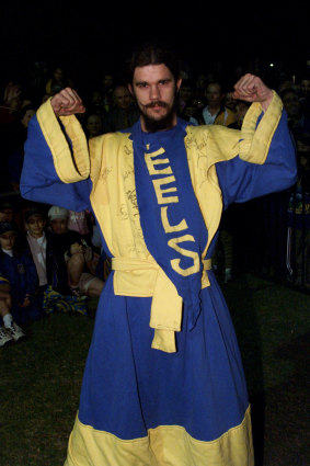 John Ryan posing in his blue-and-gold vestments in 2001 at an Eels function with players and fans.