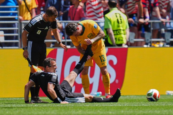 Germany’s referee Felix Zwayer is assisted by Australia’s Aiden O’Neill after cramping.