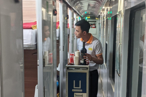 A staff member on the Lotus Express offers drinks to passengers.
