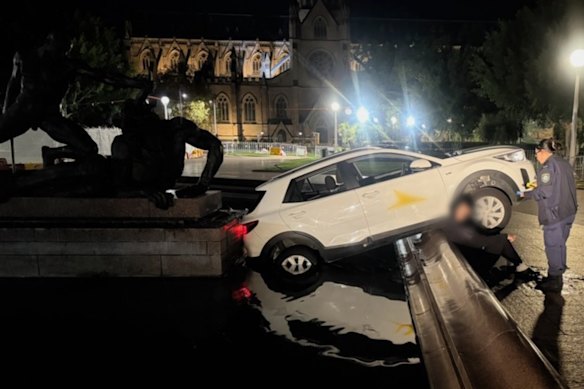 El conductor se sienta en el borde de la fuente mientras la policía realiza una prueba de alcoholemia. 