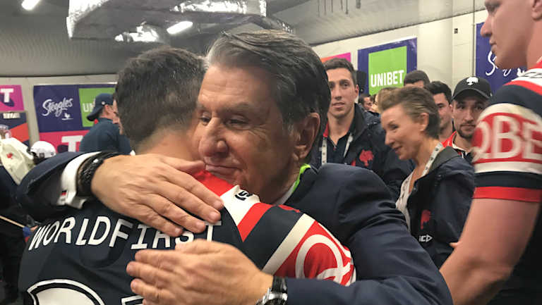 Gratitude: Nick Politis and Cooper Cronk embrace in the dressing room after the grand final victory.