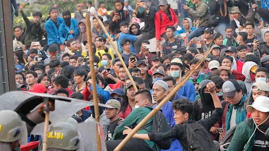 Student protesters throw projectiles at riot police outside the parliament building in Jakarta, Indonesia, on Tuesday.