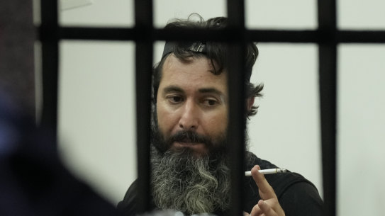 An armed man talks to hostages inside a bank in Beirut, Lebanon, Thursday, Aug. 11, 2022. A Lebanese security official says a man armed with a shotgun has broken into a Beirut bank, holding employees hostage and threatening to set himself ablaze with gasoline unless he receives his trapped saving. (AP Photo/Hussein Malla)