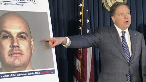 US Attorney Geoffrey Berman points to a photo showing Lawrence Ray during a news conference.