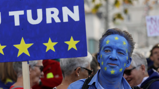 A demonstrator wears face paint in a European Union flag design as he holds a sign reading 'A EU TURN' ahead of the anti-Brexit People's Vote march, in London, UK.