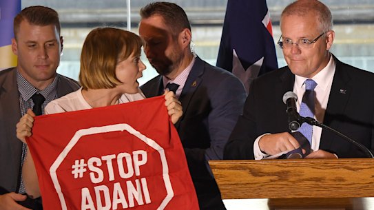 Not about to depart centre stage: An anti-Adani protester about to be led away after interrupting Prime Minister Scott Morrison's speech in Brisbane on Monday. 