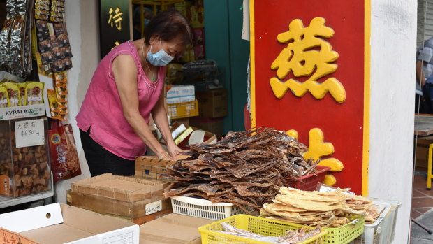 A vendor wearing a face mask prepares to display traditional Chinese medicinal products.