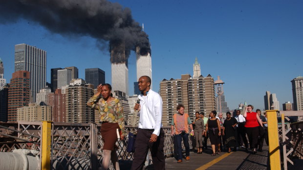 People walk across the Brooklyn Bridge as smoke billows from the twin towers on September 11, 2001. Walking was the only way out of the city that day.