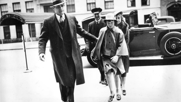 Accompanied by a bodyguard, a nurse, and a chauffeur, Gloria Vanderbilt enters the home of her mother for an Easter weekend visit in 1935.