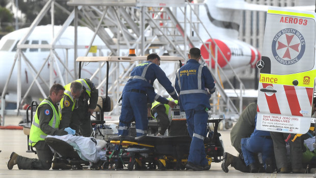 A survivor of the volcano eruption being removed on a stretcher from an RAAF Hercules at Sydney Airport on Thursday.