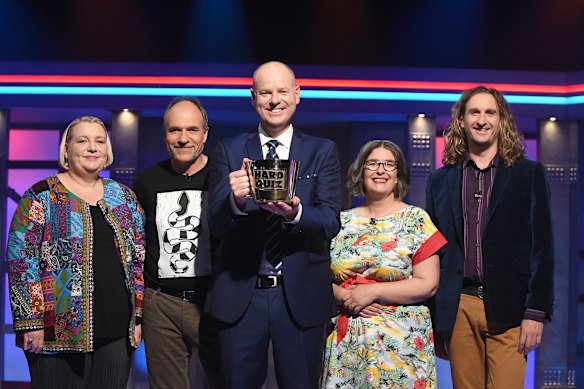 Hard Quiz host Tom Gleeson, holding the Big Brass Mug, with contestants. 