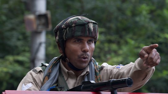 An Indian Paramilitary soldier orders a Kashmiri man to turn back near a temporary check point during curfew in Srinagar, Indian controlled Kashmir.