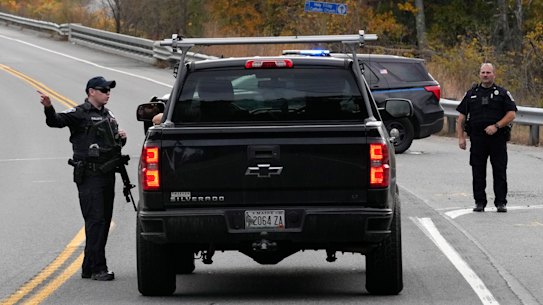 Police officers speak with a motorist at a roadblock in Lisbon, Maine.