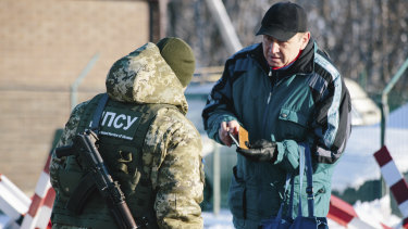 A Ukrainian border guard checks documents of a man who is going to cross the border to Russia at the checkpoint  with Russia in Hoptivka, Ukraine, on Friday.