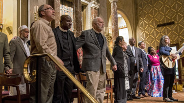 Elected officials, civic leaders and clergy join arms and sing together at the conclusion of an Interfaith Vigil of Solidarity and Hope at Rodeph Shalom in Philadelphia on Sunday.