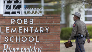A state trooper walks past the sign for Robb Elementary School in Uvalde, Texas.