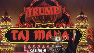 Donald Trump stands next to a genie lamp as the lights of his Trump Taj Mahal Casino Resort mark its grand opening in 1990.