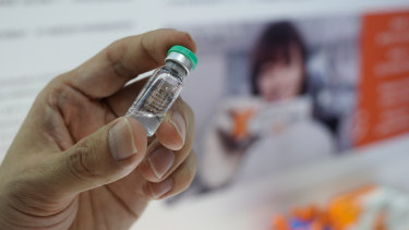 An employee shows a Sinovac COVID-19 vaccine candidate at the trade fair in Beijing.