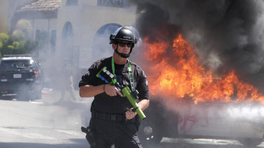 A police officer stands guard while a police vehicle burns in Los Angeles during a protest over the death of George Floyd.
