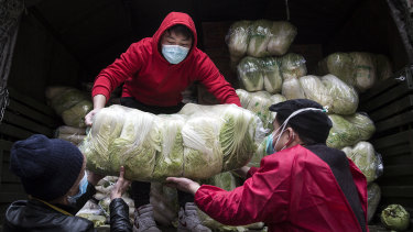 Employees wear protective masks while carrying vegetables from trucks at a hospital in Wuhan. 