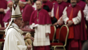 Pope Francis holds a statue of baby Jesus as he leaves at the end of the Christmas Eve Mass in St. Peter's Basilica.