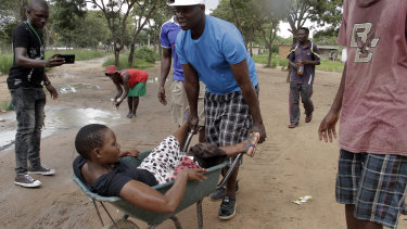 A woman with a wounded leg during clashes between protesters and police is transported in a wheelbarrow, during the protests in Harare.
