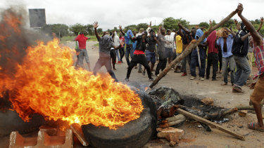 Protesters gather near a burning tyre during a demonstration over the rise in fuel prices in Harare, Zimbabwe, on Tuesday.