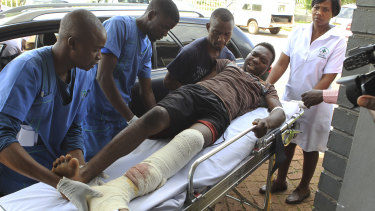 An injured man is helped at a private hospital after an alleged assault by a group of uniformed soldiers.
