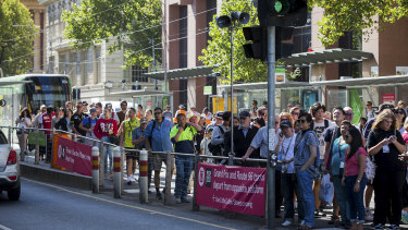 Sports fans crowd a tram stop at the corner of Collins and Spencer streets.