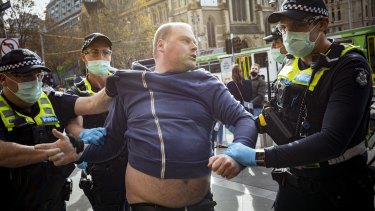 An anti-vaccination protestor is arrested outside Flinders Street Station after hijacking a small business owners protest. 