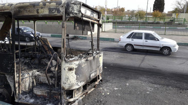 Cars drive past a scorched public bus that remained on the street after protests that followed authorities' decision to raise gasoline prices, in Tehran, Iran.