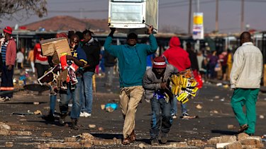 Looters carry items at Letsoho Shopping Centre in Katlehong, east of Johannesburg, South Africa.