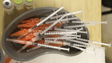 Medical personnel place pre-loaded syringes in a container during a vaccination push in New Orleans.