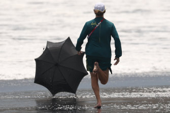 Australian medical officer Jason Patchell  chases an umbrella down Tsurigasaki beach in typhoon conditions on day four of the Tokyo Olympics surfing competition.