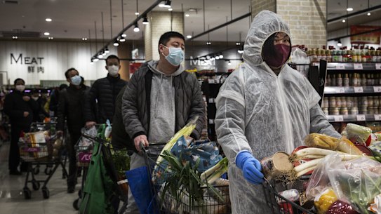 Residents wear protective gear as they line up in a supermarket in Wuhan. 