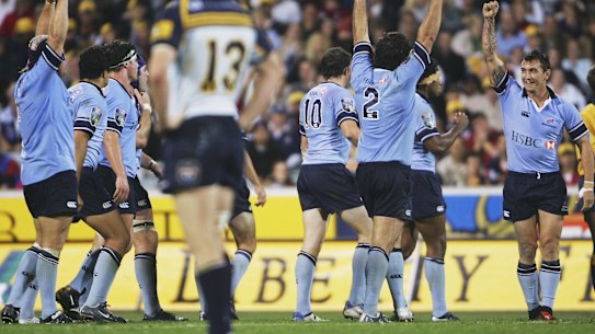 Brumbies captain Stirling Mortlock stands dejected as Waratahs players celebrate victory at Canberra Stadium in 2005.