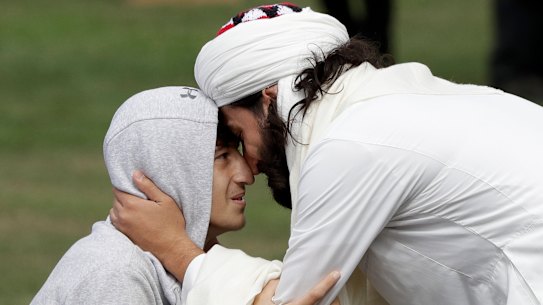 Zaid Mustafa, left, son and brother of victims from last week's mosque shootings is welcomed to Friday prayers at Hagley Park in Christchurch.