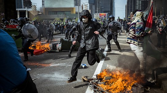 A protester jumps over a fire.