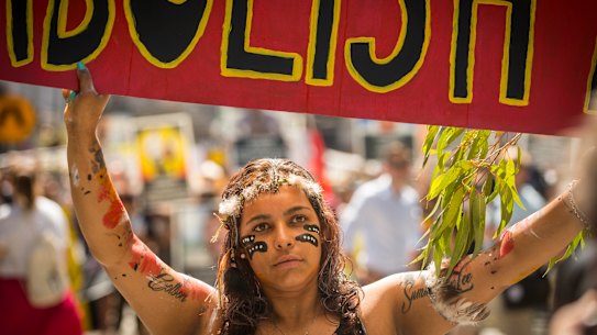 A woman carries a sign calling for the abolition of Australia Day while taking part in a 2019 Invasion Day march in Melbourne.