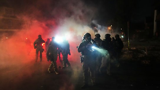 Police officers stand at the scene amidst tear gas.