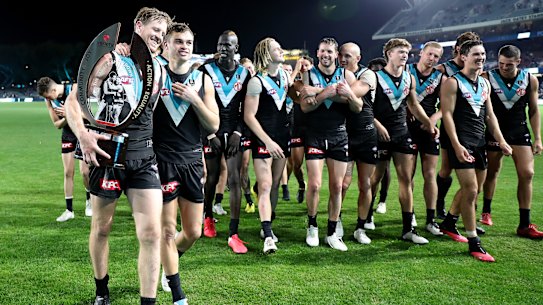 Tom Jonas, Karl Amon and Port players walk off with the Showdown Trophy after beating Adelaide on Saturday night.