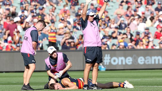 Jake Kelly of the Crows lays on the ground after a clash with Patrick Dangerfield.