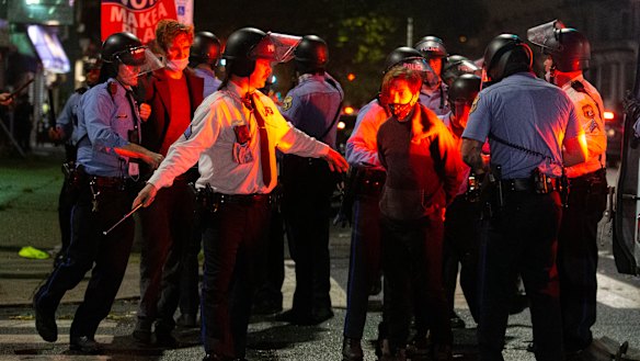 Police arrest people after an officer was struck by a brick during a violent protest after police shot and killed a black man on a Philadelphia street.
