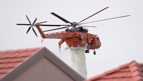 An air-crane drops water to assist firefighters as they battle a grass fire in Taylors Lakes on Monday.