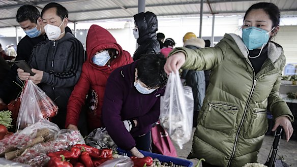 Wuhan residents wear masks to buy vegetables.