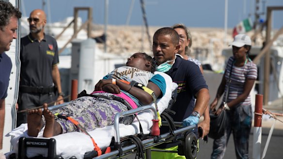 A woman is carried away on a stretcher after disembarking from an Italian Coast Guard ship in the port of Pozzallo, Southern Italy, on Sunday.