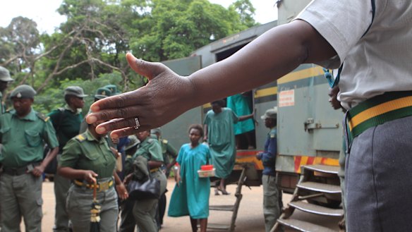 A prison guard directs some of the people arrested during protests as they arrive to make their magistrates court appearance on Thursday.