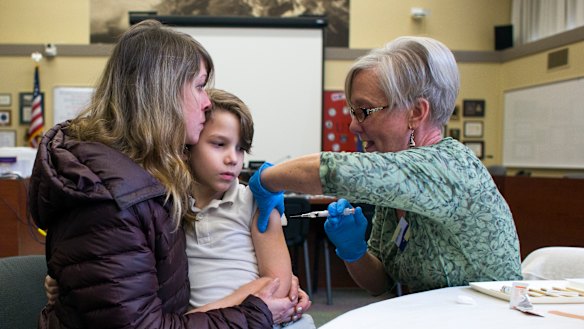 A woman holds her son as a nurse administers an immunisation in Oregon. 