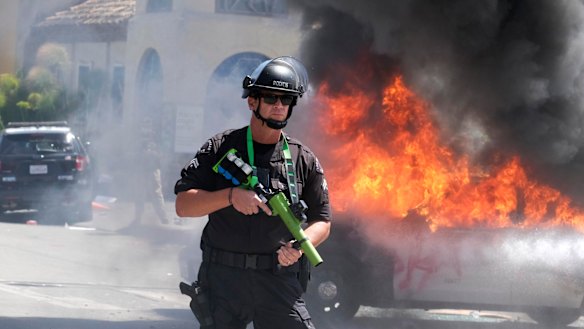 A police officer stands guard while a police vehicle burns in Los Angeles during a protest over the death of George Floyd.
