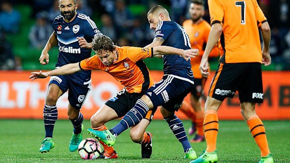 James Troisi of the Melbourne Victory (blue) and Brett Holman of Brisbane Roar (orange) contest the ball during their A-League Semi-Final at AAMI Park on April 30, 2017.
